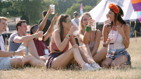 friends sitting on grass watching a gig at a music festival