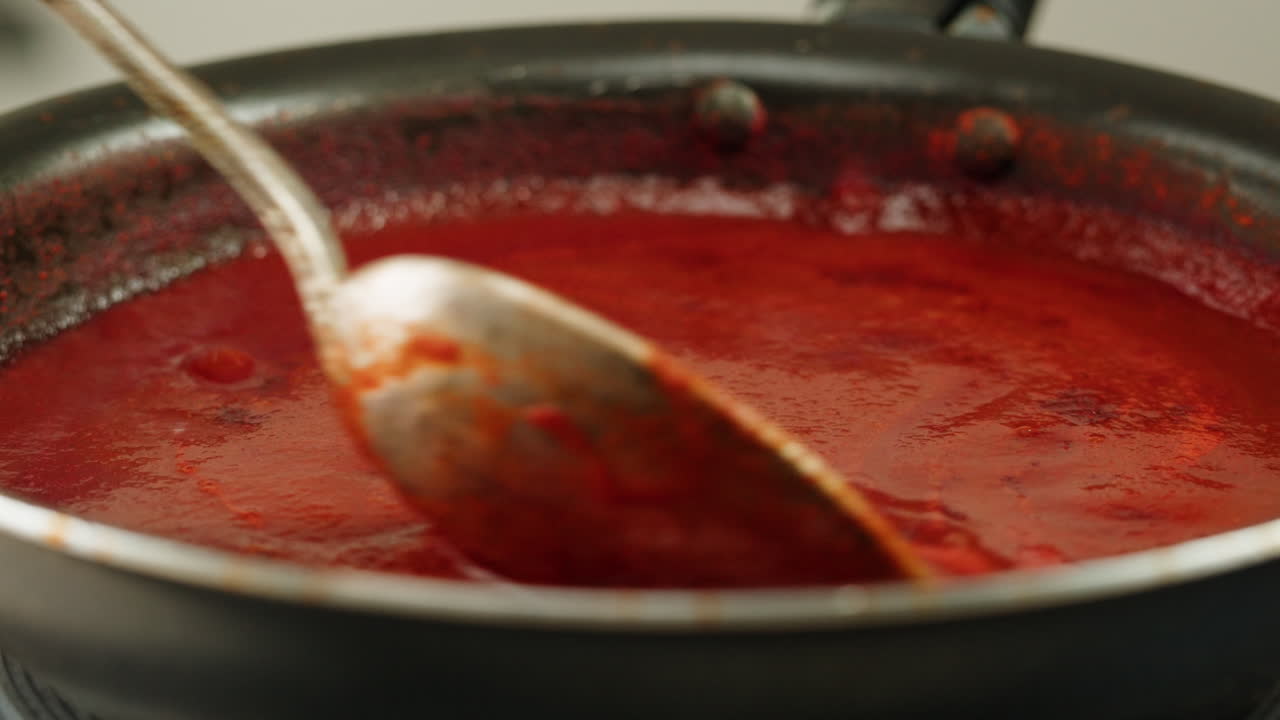 Chicken in tomato sauce is boiling on a frying pan with spices. Cooking tomato sauce curry with chicken fillet. Traditional Italian Mexican Asian dish. High quality studio shot for cafe, restaurant close up.