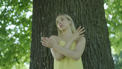 woman in yellow dress dancing by tree in summer park