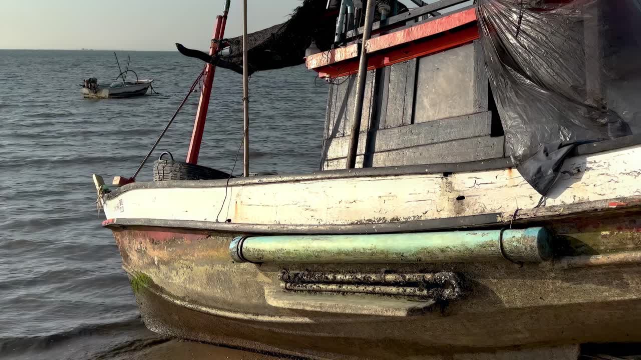 A close-up of an old boat's side with a calm sea in the background.