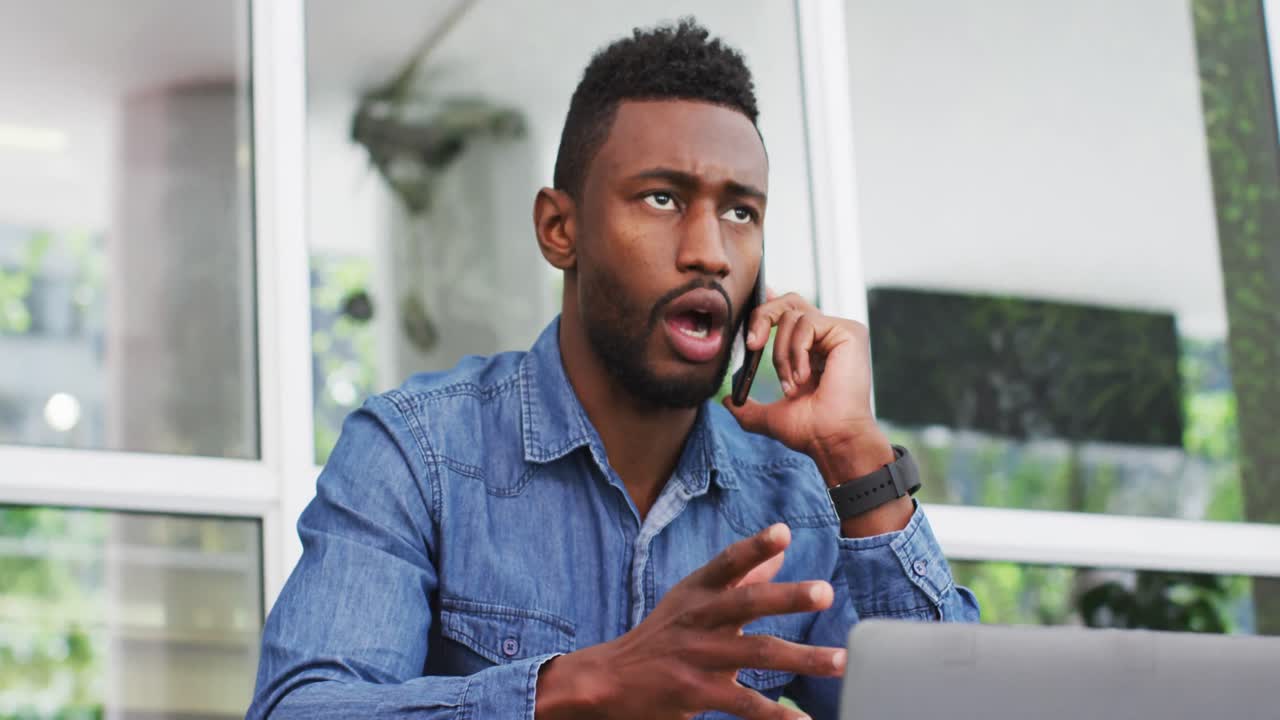 African american businessman talking on smartphone and using laptop outisde cafe cmmunication, busin