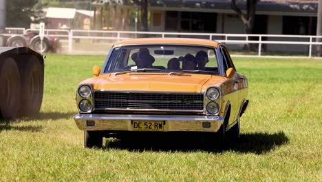 vintage vehicle driving slowly across a grassy area