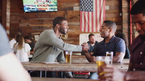 two male friends meeting in sports bar enjoying drink before game