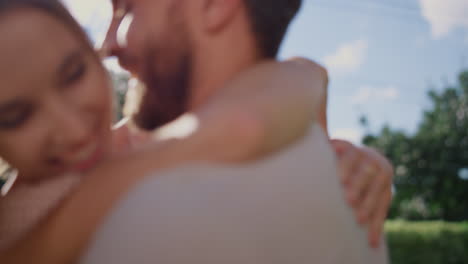 happy woman hugging man in park. husband turning around woman on hands