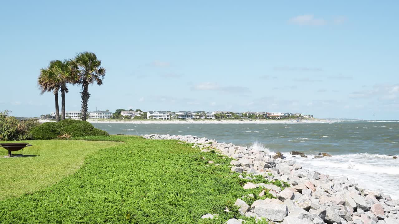 amplia toma estática de un patio trasero frente al mar con casas en el fondo