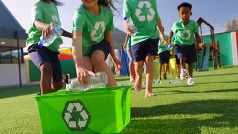 Side-view-of-Caucasian-female-teacher-teaching-schoolkids-about-bottle-recycle-in-the-school-playgro