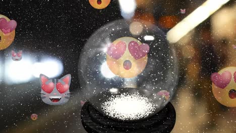 animation of christmas snow globe and emoji icons with red hearts eyes with snow falling