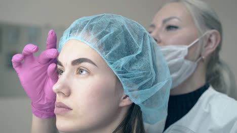 girl and cosmetologist look at brows with permanent makeup