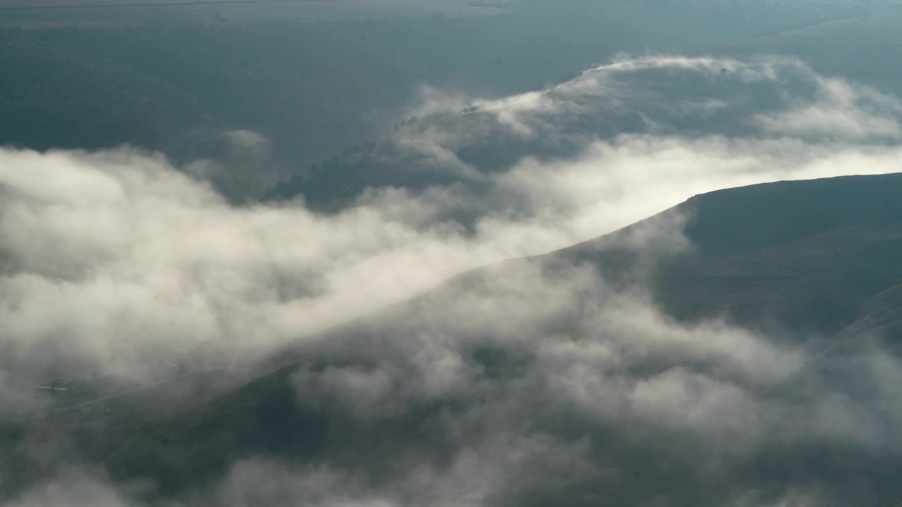 Luftfoto af morgentåge, der ruller ind over bakkede landskaber