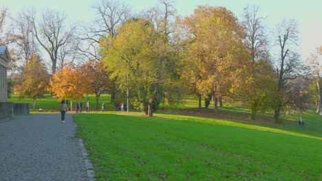 people walking at the schlossgarten park with autumnal trees on a sunny day in stuttgart, germany. - wide shot