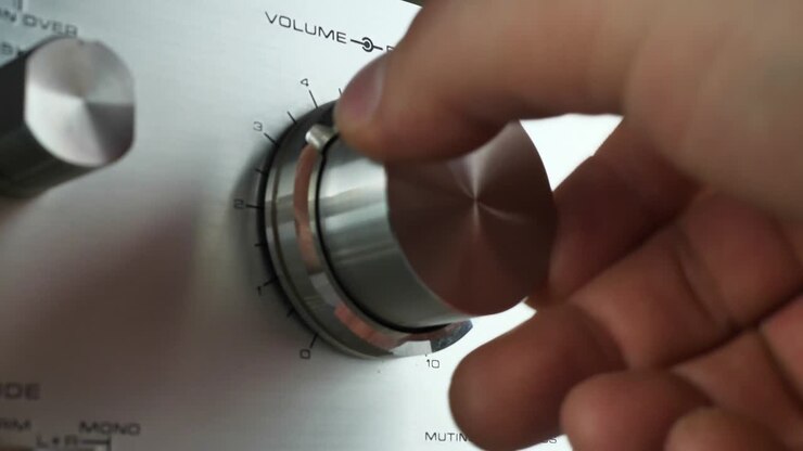 hand turn on the volume. turn the knob on the stereo, adjust the volume. the man makes the music louder, close up