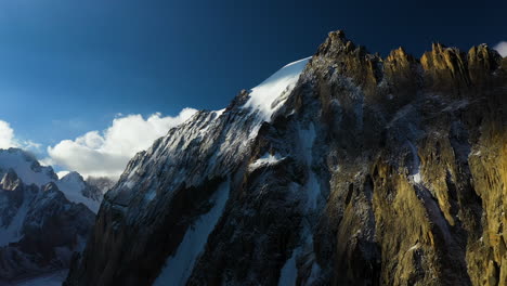 Epic-cinematic-rotating-drone-shot-of-a-half-snowy-mountain-top-in-the-Ak-Sai-glacier-in-Kyrgyzstan