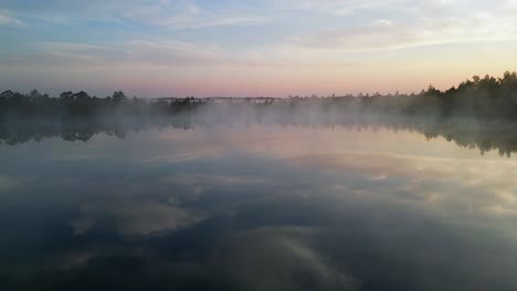 Paso-Elevado-De-Una-Conífera-Solitaria-A-Un-Pequeño-Lago-Brumoso-Que-Refleja-El-Cielo-Del-Amanecer