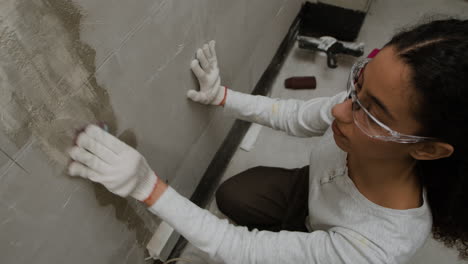 woman sanding a wall