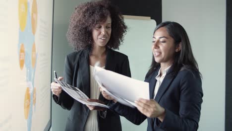 jóvenes empresarias hermosas discutiendo el informe y sonriendo
