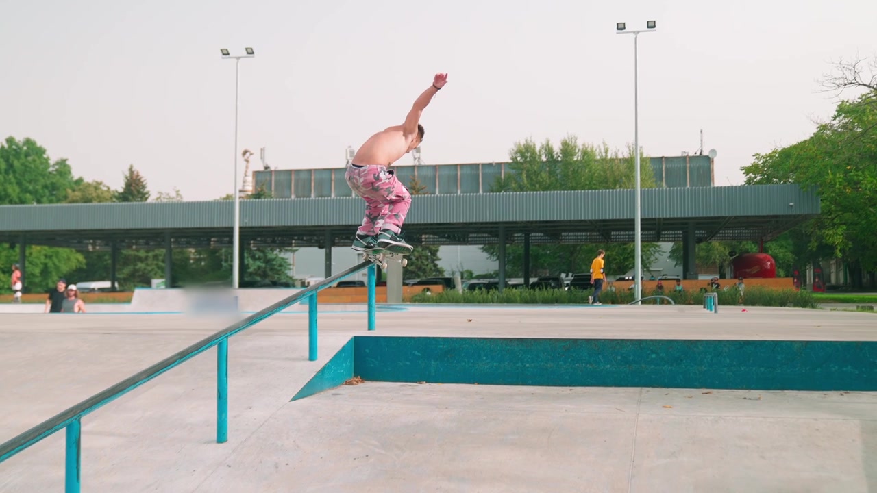 Ung mann som utfører et skateboard grind-triks på en rail i en skatepark