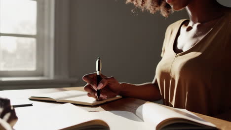 a black woman studying or writing in a journal by a window