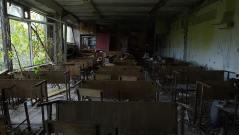 zoom in view of abandoned classroom with furniture in pripyat