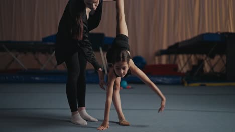 young gymnast training with her coach on the floor