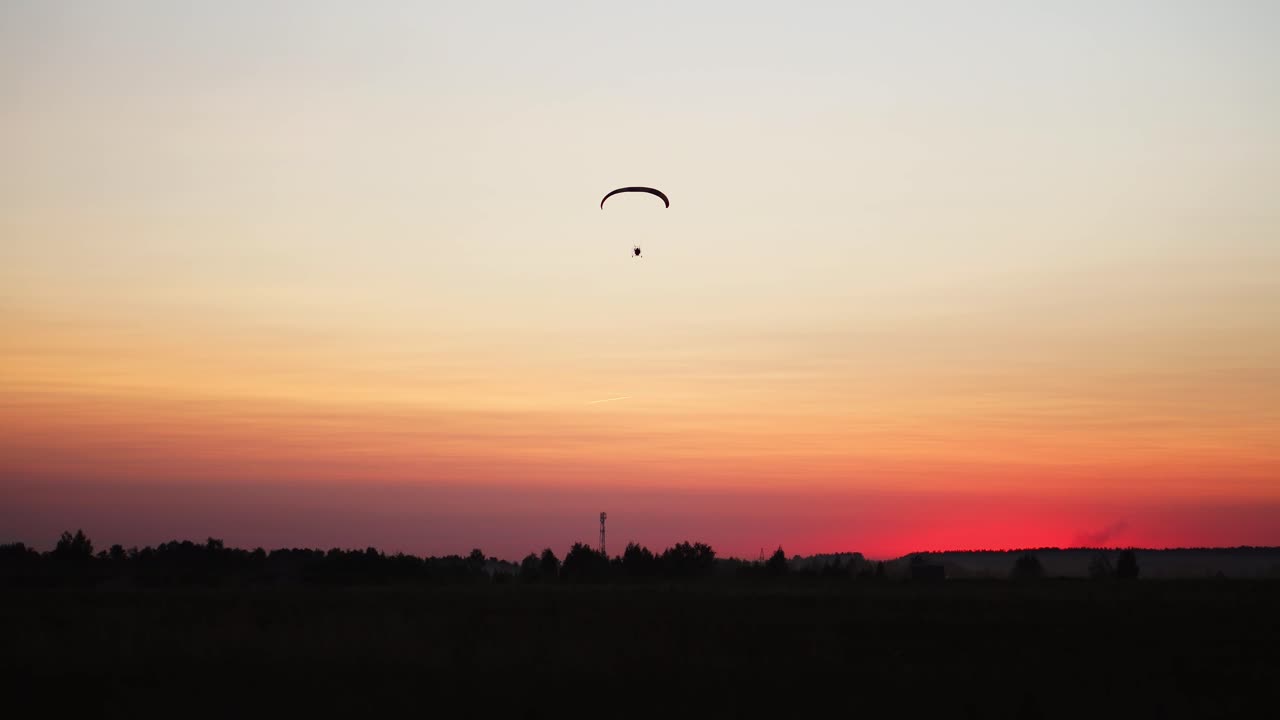 el piloto de un parapente vuela desde la cámara alejándose gradualmente en la distancia contra el hermoso cielo al atardecer. hermosa imagen de fondo de fondo. concepto de libertad