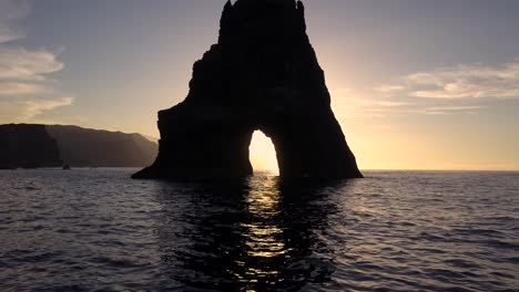 madera island, portugal - natural rock formation with a hole surrounded by calm sea water during sunset - aerial drone shot