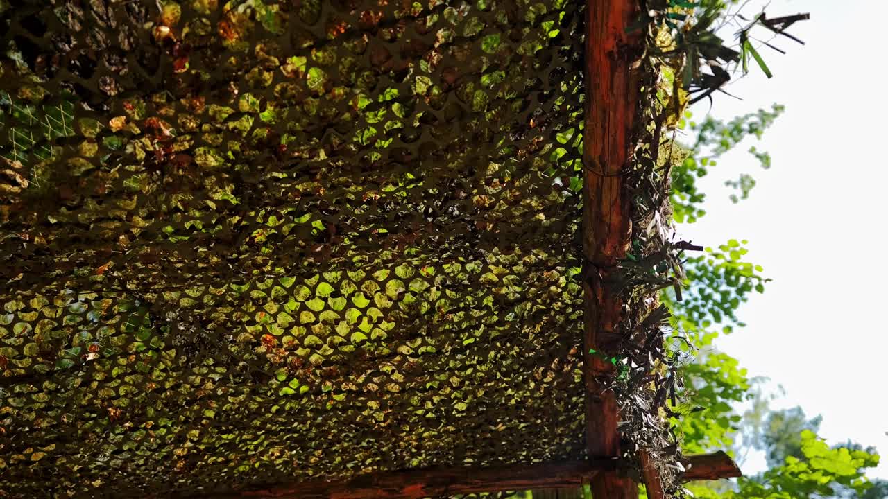 Close-up of camouflage netting stretched over wooden war tunnel frame