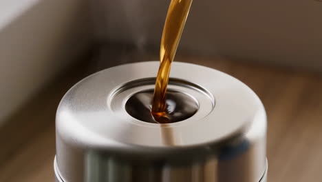 coffee being poured into a stainless steel thermos