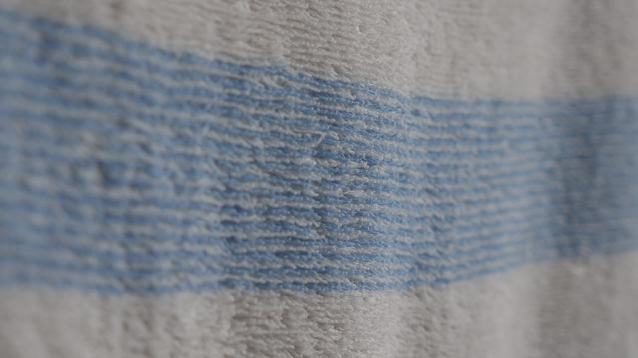 A hand gently touches a textured blue-striped fabric creating a sense of comfort and warmth