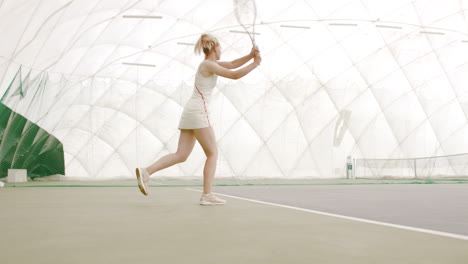 WIDE-SIDE-VIEW-Young-Caucasian-female-tennis-player-hitting-a-ball-during-game-or-practice.-100-FPS-slow-motion,-4K-UHD-RAW-graded-footage