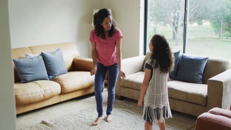 Happy-mixed-race-mother-and-daughter-dancing-in-living-room