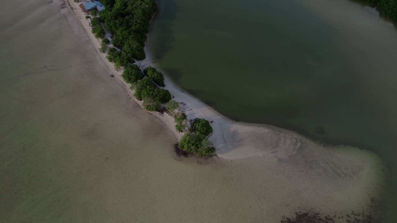 드론은 열대 해변을 위에서 아래로 바라보며 우아하게 회전하며, 위로 기울기 전에 조용한 해안선을 드러니다.