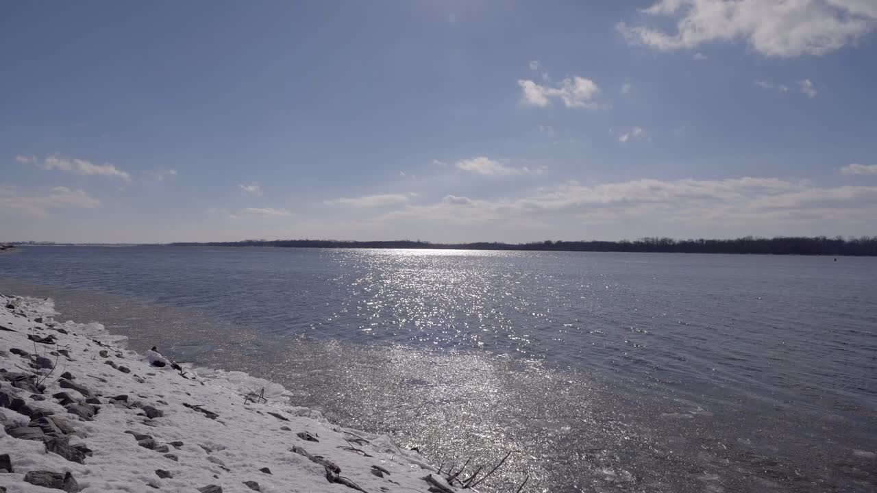 Waves flowing on the river by snow covered rocks in winter