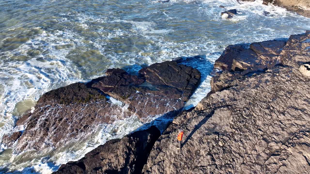 Drone view man on rocks looking at rough Atlantic seas Hook Head Wexford Ireland spring tides