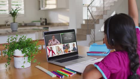 Schoolgirl-using-laptop-for-online-lesson-at-home,-with-diverse-teacher-and-class-on-screen