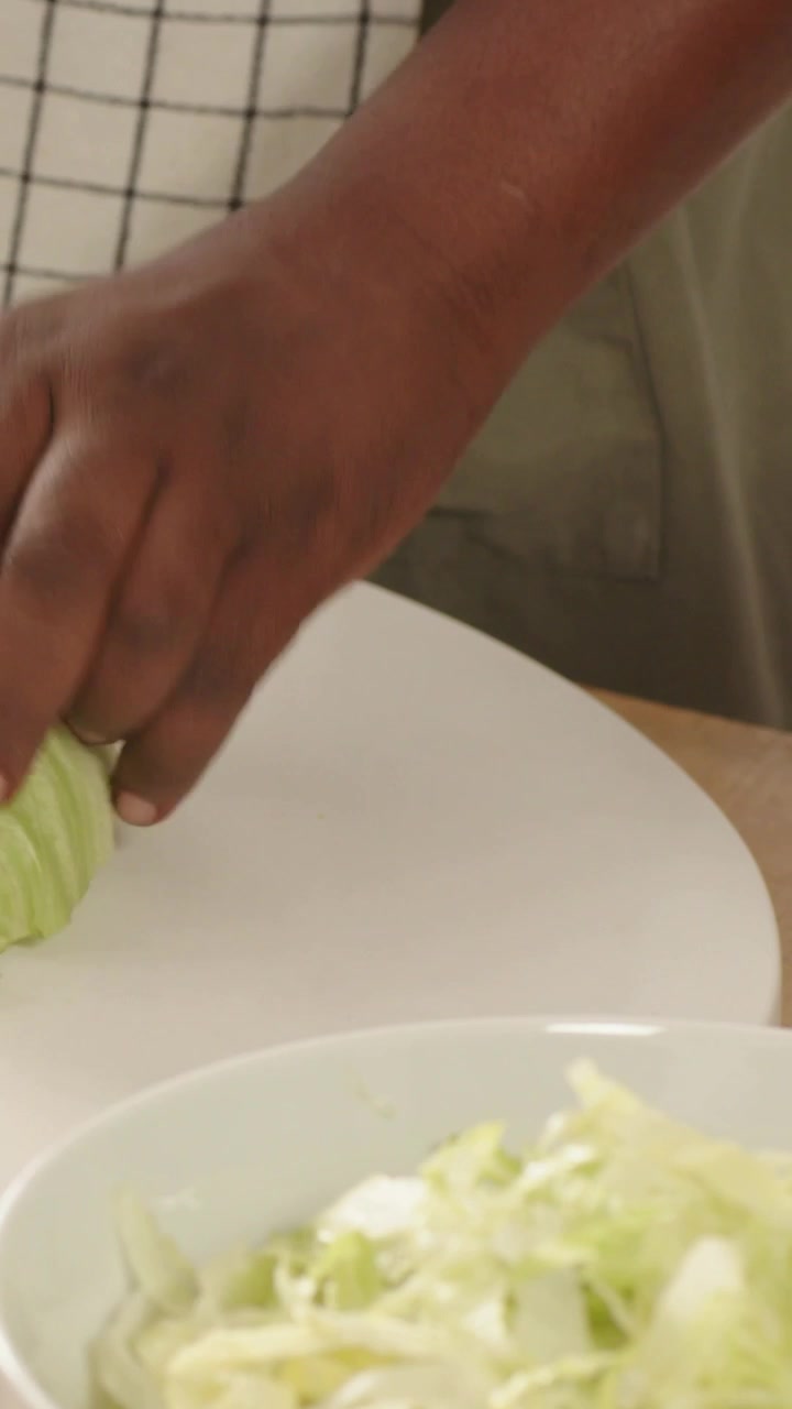 Video verticale: Mano che afferra e strappa il cavolo in cucina, aggiungendo i pezzi in una ciotola per l'insalata, grembiule.