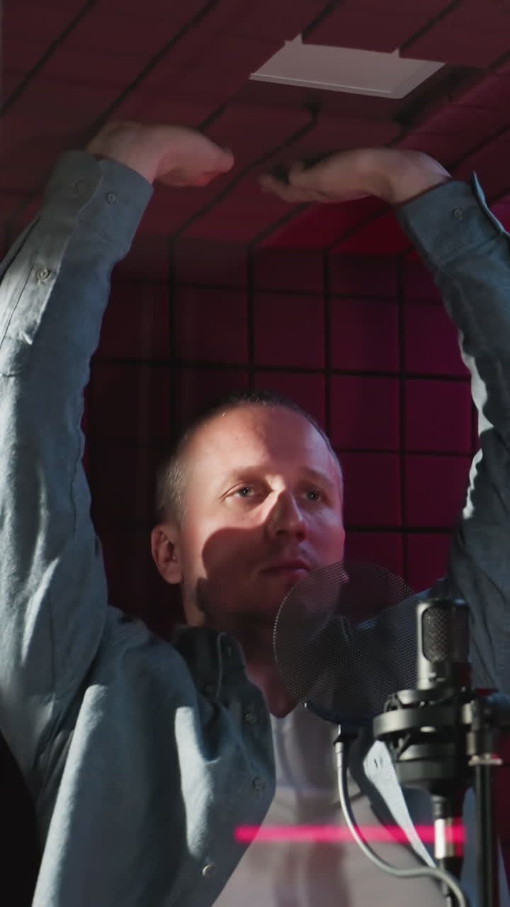 un hombre con una camisa de manga larga azul y interior blanco se extiende hacia arriba, tocando el techo y las paredes laterales de una habitación a prueba de sonido roja, resaltada por una vibrante iluminación led
