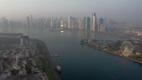 4k: drone view of sharjah's khalid lake with city skyline and eye of emirates on an early morning in the united arab emirates