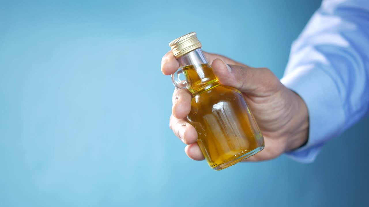 mano sosteniendo una pequeña botella de aceite de oliva