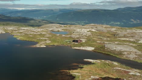 A-small-wooden-hut-on-the-shore-of-the-mountain-lake-in-the-Korgfjellet-mountain-range
