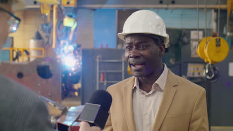african american factory engineer giving interview to tv journalist