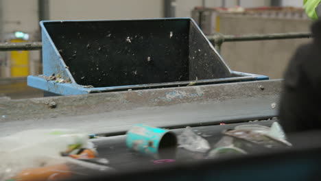 people sorting plastic bottles and aluminum cans on a conveyor belt in a recycling plant