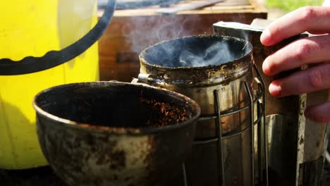 beekeeper preparing bee smoker on truck