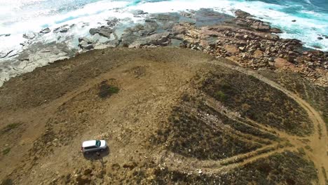 a car stops on a remote point by the ocean and a man gets out, aerial