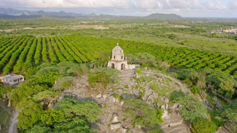 drone view of san martin de porres shrine on hill next to mango farm, bani, dominican republic