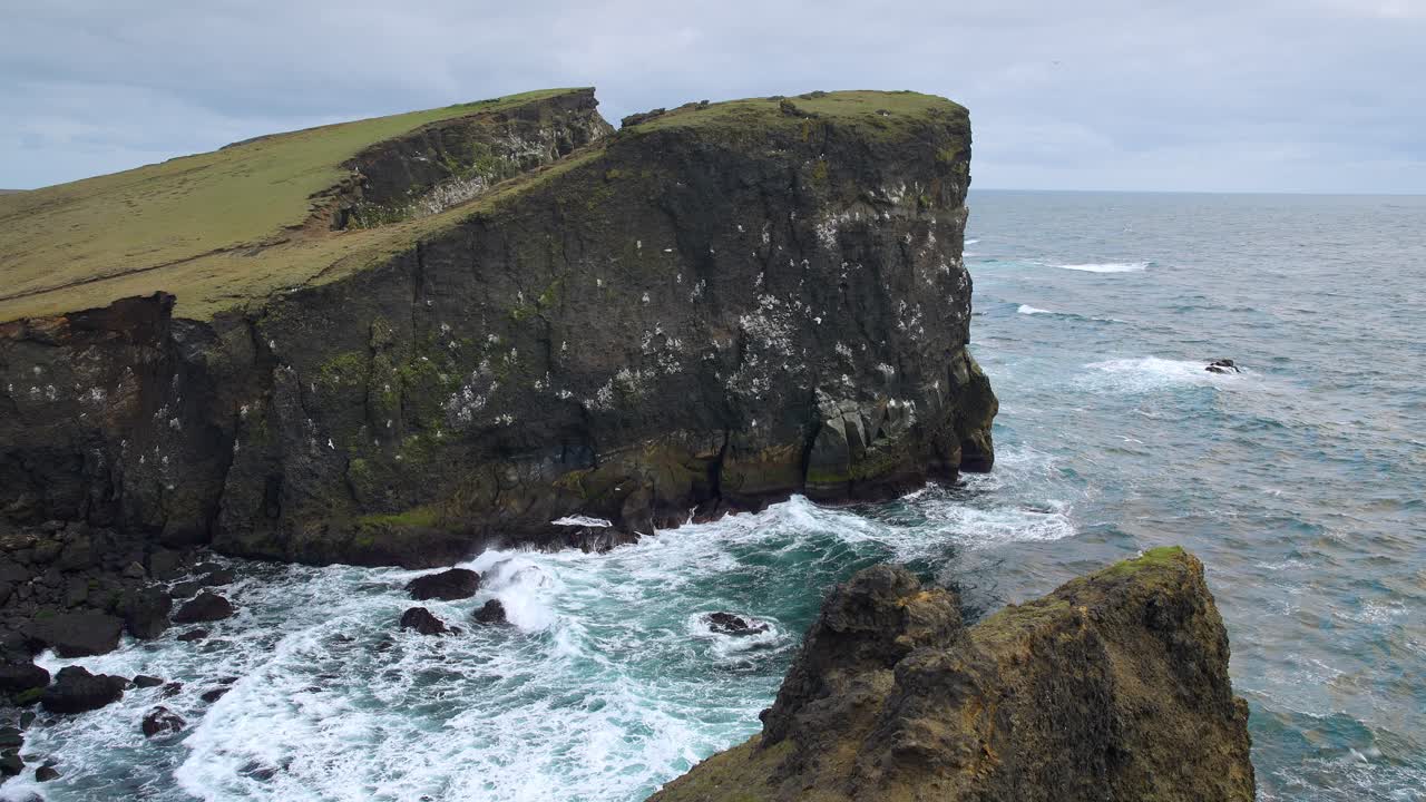 un impresionante acantilado costero de valahnúkamöl con olas que se estrellan contra las rocas y gaviotas que se deslizan en el viento
