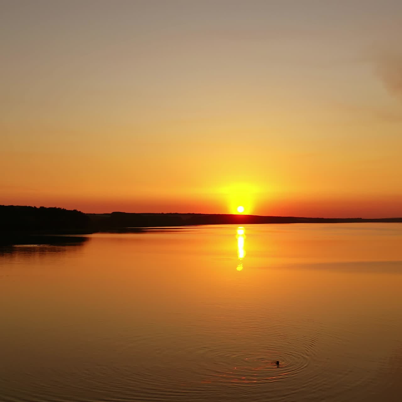 Beautiful sunset over the river. Amazing landscape of the evening water with the golden path from the setting sun. Wonderful lake at sunset. Motion camera to the left.