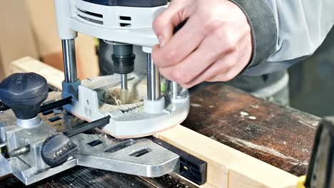 close-up of a carpenter's hand working with an manual electric cutter in a home workshop.