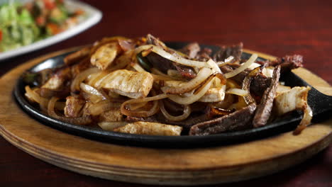 steam rises from sizzling skillet of combination beef and chicken fajitas with onions and peppers, slider close up 4k