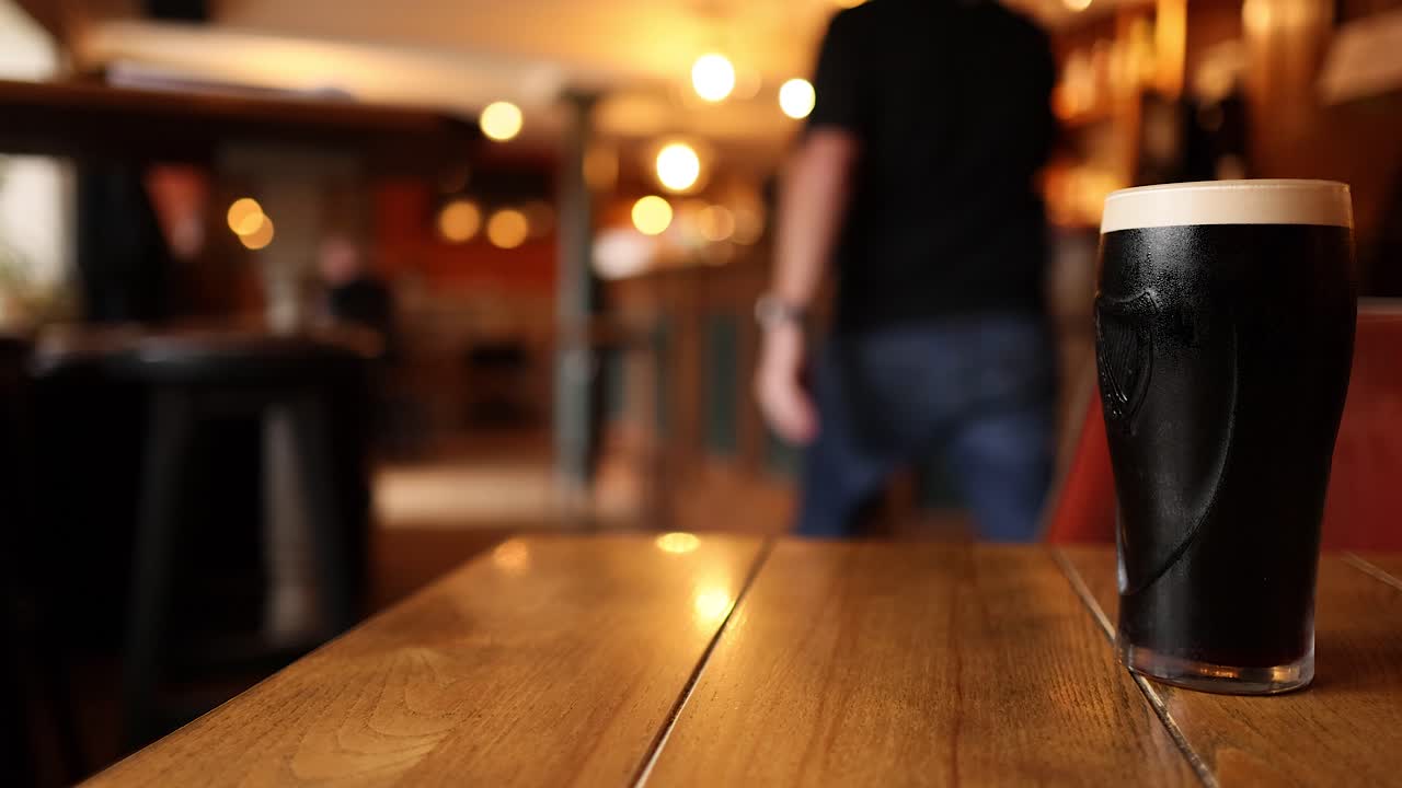 hombre camina hacia la cerveza en la mesa del pub