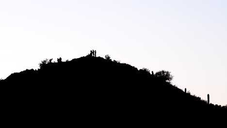 silhouettes of five people on the top of a mountain, extreme wide shot